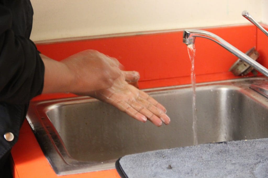 Hands being washed at sink; English students learn proper hand-washing technique to prevent spread of coronavirus