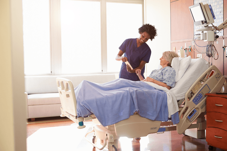 A medical professional assists an elderly woman in a hospital bed