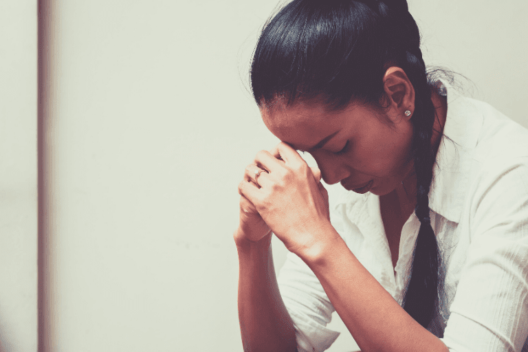 Woman looking down with hands clasped