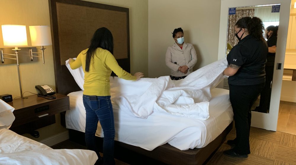 Housekeeping students practice making bed in hotel room
