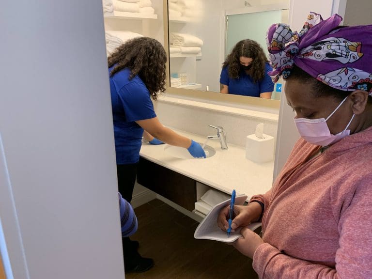 Housekeeping student takes notes during training in hotel bathroom