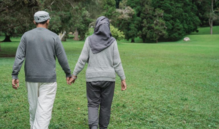 Halmai and Zahra hold hands and walk in a park.