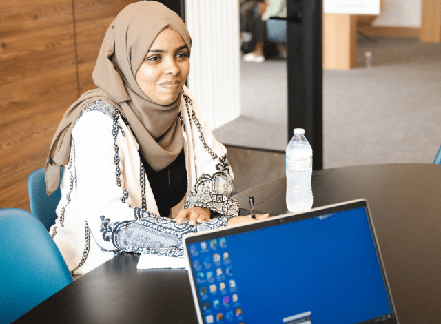 A woman in a hijab sits at a meeting