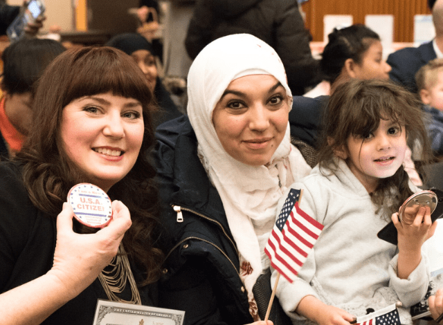 Two women and a child smile during a naturalization ceremony to become U.S. citizens.