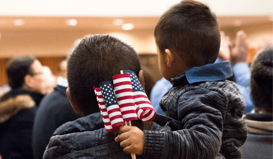 A boy holds an American flag at a citizenship ceremony.