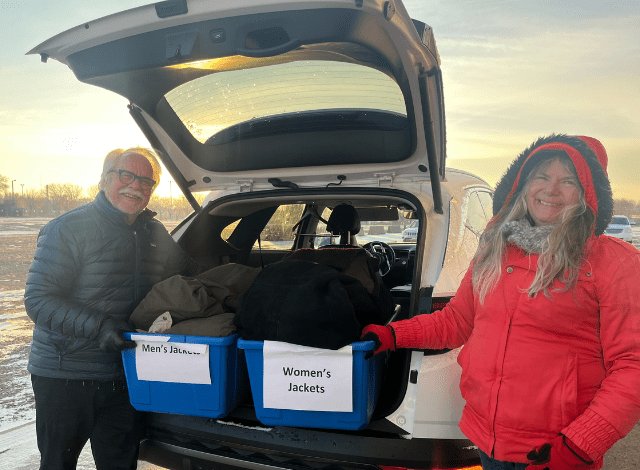 Two people deliver coat donations