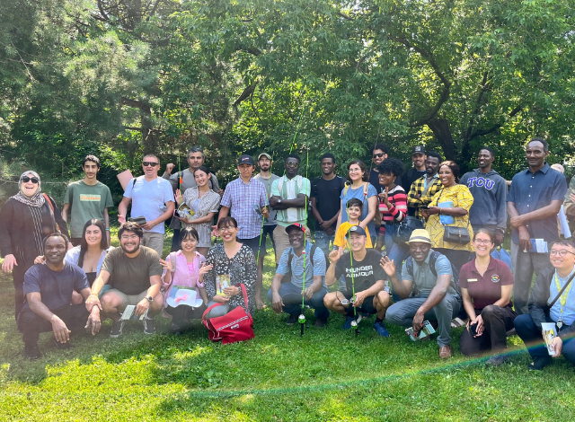 A group of New Americans gather on bright green grass