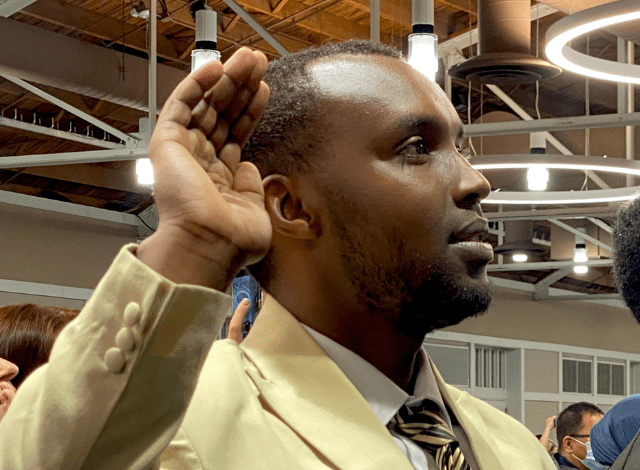 A man raises his right hand during a naturalization ceremony,