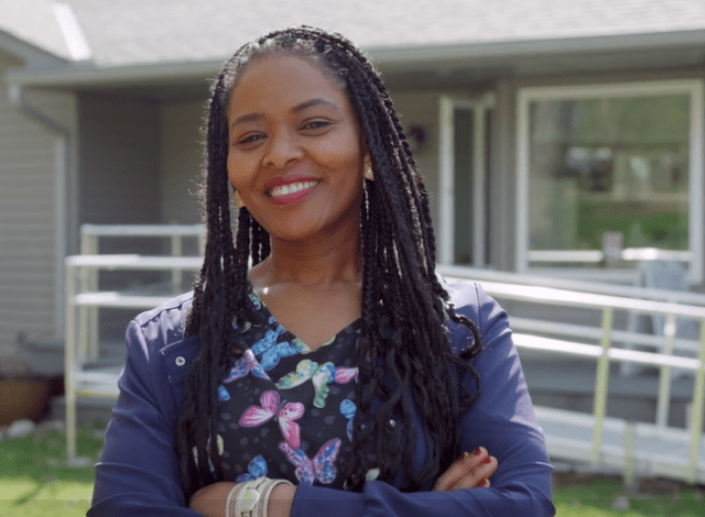 A black woman with long braids wearing nursing scrubs