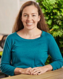 Woman with straight, light-brown hair in a long-sleeved turquoise shirt.