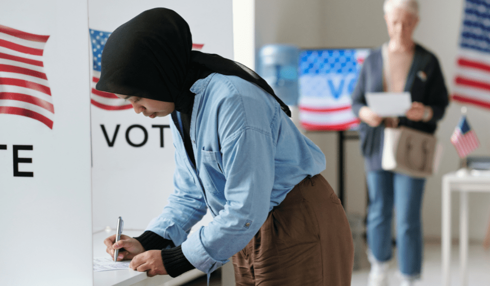 Woman in a black hijab casts her voting ballot