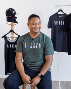 A man in a gray t-shirt smiling and looking to the side