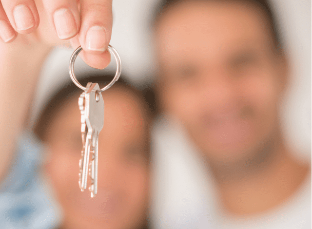 Blurred image of a woman and man holding up keys