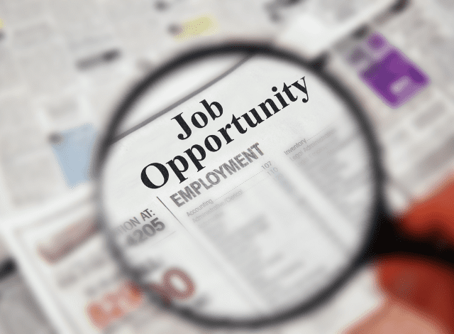 A magnifying glass over a newspaper about job opportunities