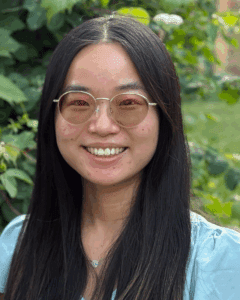 Woman with long, dark hair and glasses, smiling