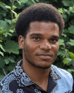 Man in a collared shirt in front of trees